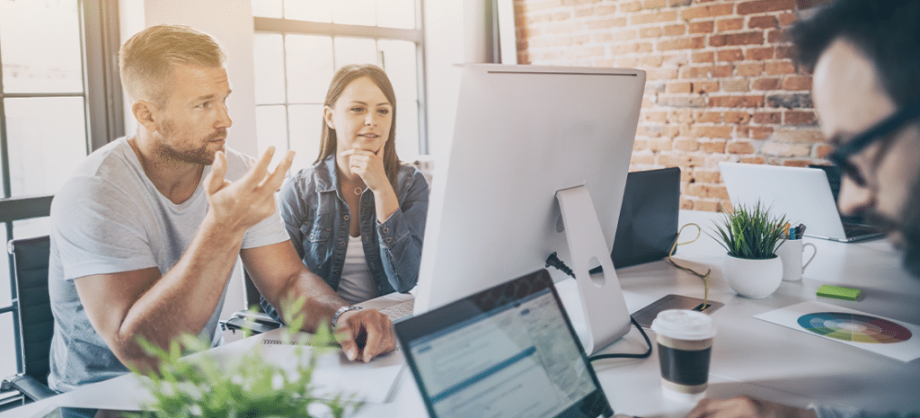 Web designers looking at computer screen inside agency office