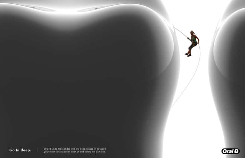 Image from award-winning "Go In Deep" campaign in which a woman repels in climbing gear down the side of a giant tooth
