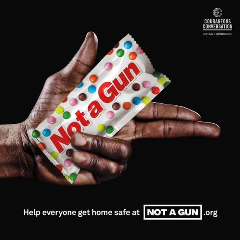 Image of a Black hand holding candy labeled "Not a Gun" from the award-winning advertising campaign of the same name aimed at advocating for police de-escalation, non-bias, and non-violence training