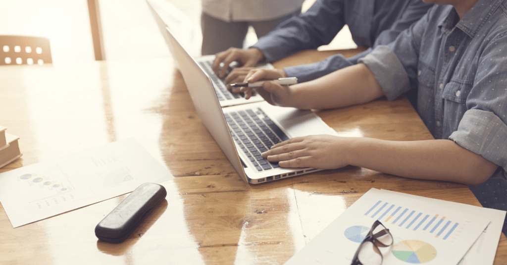 Two people working on laptops sitting side by side.