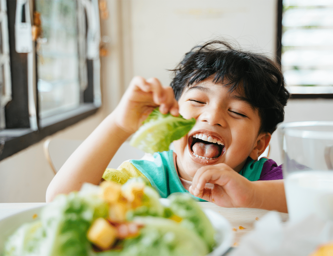 Smiling child eating healthy meal with vegetables