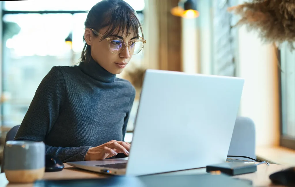 A woman at a desk looking at her computer contemplating recurring revenue opportunities for her agency.