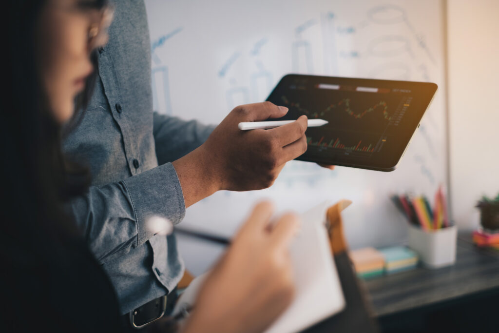 Two agency employees look at a colorful graph on a tablet.