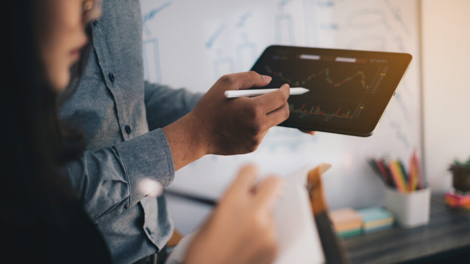 Two agency employees look at a colorful graph on a tablet.