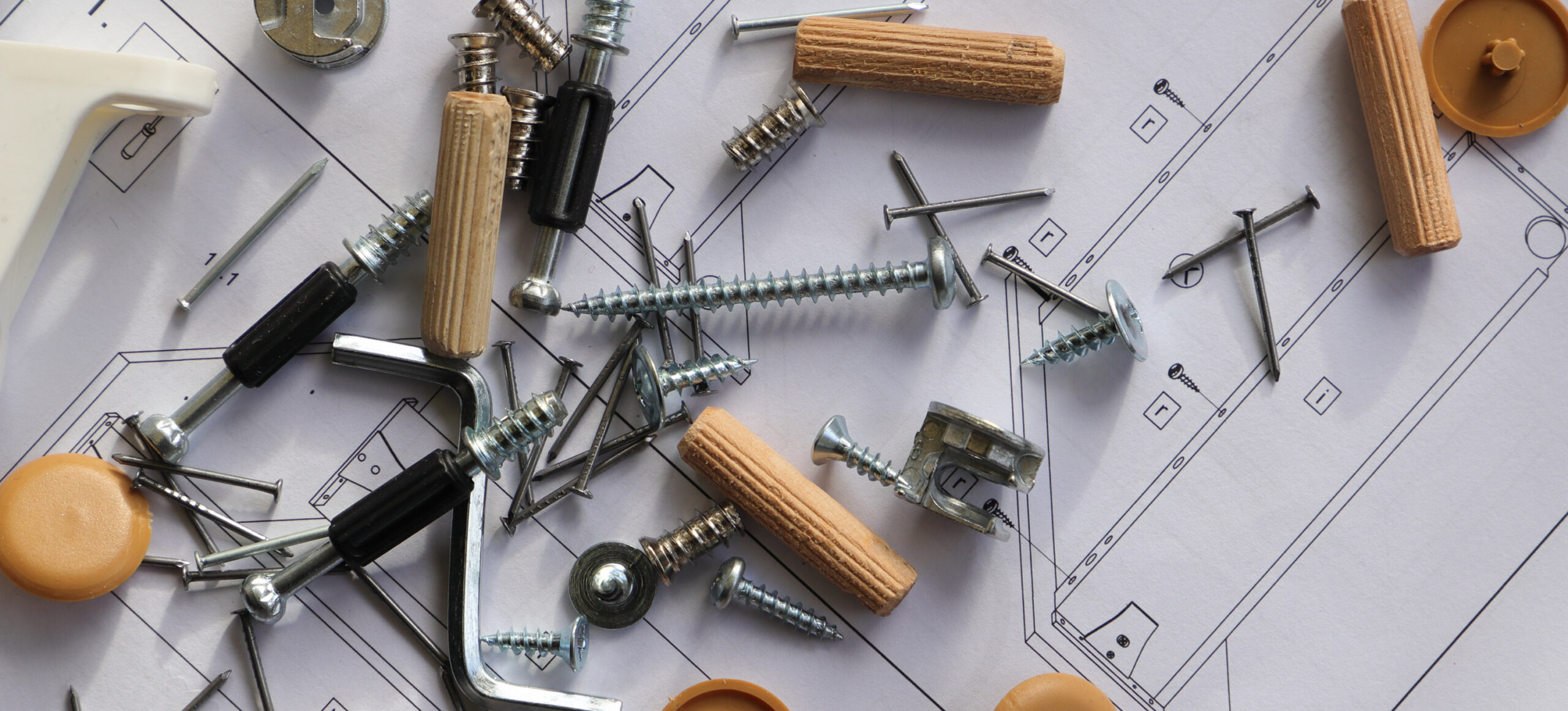 Instructions for assembling furniture with a pile of furniture hardware on top of them.